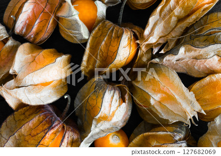Cape Gooseberries With Shells on Black Rock Surface Cape Gooseberries With Shells on Black Rock Surface 127682069