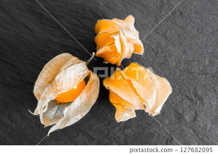 Cape Gooseberries on Black Rock Surface Background Cape Gooseberries on Black Rock Surface Background 127682095
