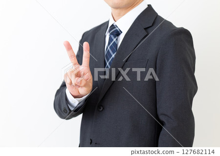 Middle-aged male businessman in a suit making a peace sign 127682114