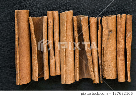 Dried Cinnamon Sticks Placed Vertically on Black Stone Surface Background Dried Cinnamon Sticks Placed Vertically on Black Stone Surface Background 127682166