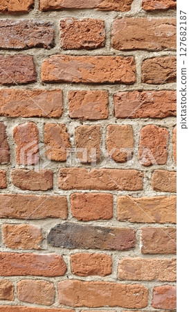 Close-up view of a textured red brick wall with visible mortar lines. The image symbolizes strength, construction, and classic architectural elements 127682187