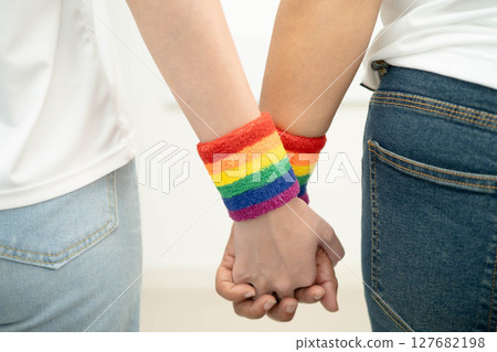 Asian LGBT couple woman holding hand wearing rainbow wristband. Asian LGBT couple woman holding hand wearing rainbow wristband. 127682198