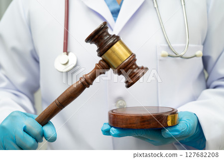 Asian doctor holding court hammer for and crime law justice, forensic medicine. 127682208