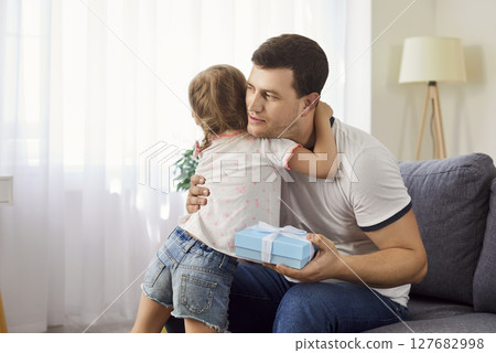 Loving daughter giving her father gift for Father Day, happy family celebrating special occasion. Loving daughter giving her father gift for Father Day, happy family celebrating special occasion. 127682998