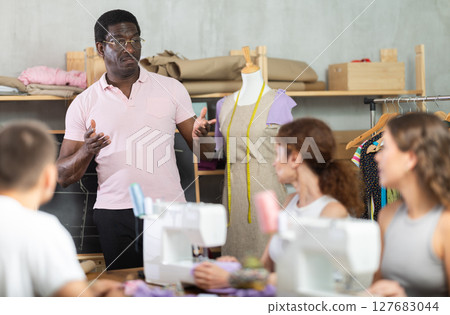Sewing school African man teacher conducts lesson for students using mannequin 127683044