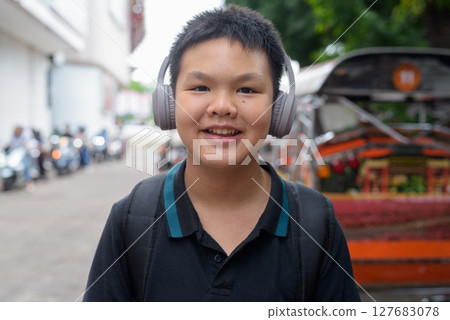 Thai boy with headphones standing by tuk tuk taxis 127683078