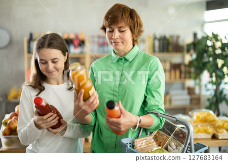 Mother and daughter choose tasty juice together in grocery section of supermarket 127683164