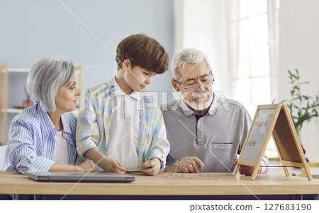 Grandparents teaching grandson to read and spell using magnetic board and letters Grandparents teaching grandson to read and spell using magnetic board and letters 127683190