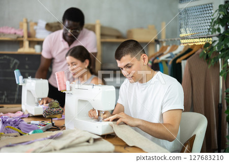 Young man working with sewing-machine during dressmaking courses 127683210