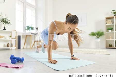 Sporty athletic young woman doing mountain climber exercise in plank pose, having workout at home. 127683214
