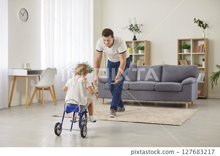 Father And Daughter Riding Tricycle At Home Spending Leisure Time Together 127683217