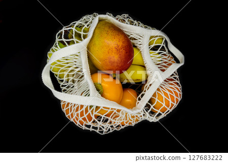 Exotic fruits in white mesh net bag and isolated on black background 127683222