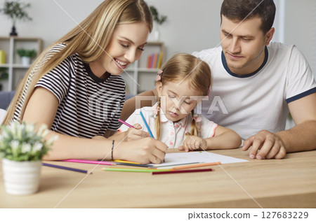 Happy family sitting at desk, drawing together, parents and daughter enjoying creativity at home. Happy family sitting at desk, drawing together, parents and daughter enjoying creativity at home. 127683229
