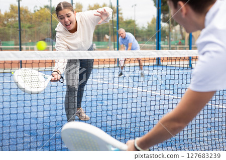 Portrait of young female in sportswear enjoying popular sport padel game on tennis court outside 127683239