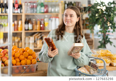 Teenage girl choosing nougat in grocery store 127683298