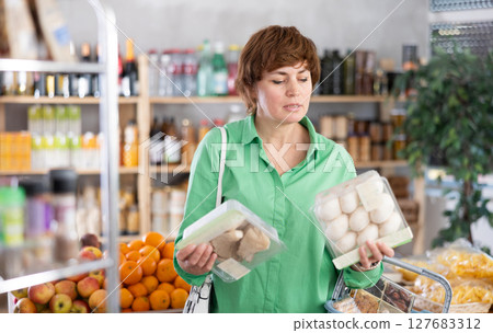 Adult woman choosing mushrooms in a package Adult woman choosing mushrooms in a package 127683312