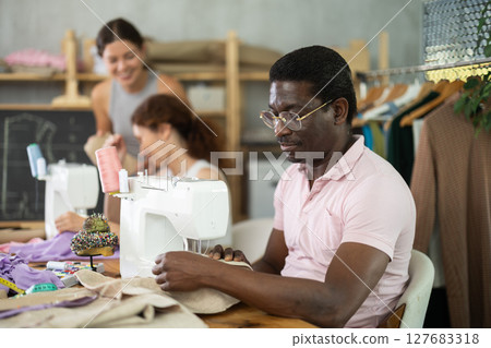 Middle-aged man working with sewing-machine during dressmaking courses Middle-aged man working with sewing-machine during dressmaking courses 127683318
