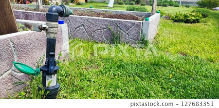 Eco-friendly garden irrigation setup with hose valve and drip system for sustainable backyard watering near raised beds Eco-friendly garden irrigation setup with hose valve and drip system for sustainable backyard watering near raised beds 127683351