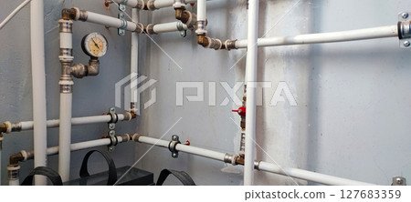Efficient home plumbing concept: interior water pressure system with PVC piping, metal fittings, and pressure gauge. 127683359
