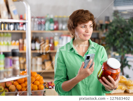 Adult woman scanning tomatoes in marinade 127683402