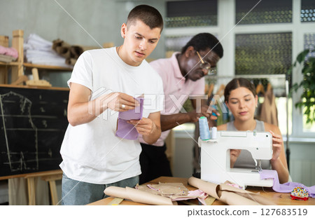 Positive young guy holding textile detail fixed on paper Positive young guy holding textile detail fixed on paper 127683519