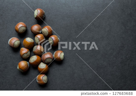 Group of Whole Hazelnuts on Black Background Surface with Free Space Group of Whole Hazelnuts on Black Background Surface with Free Space 127683688