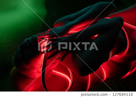 Woman poses topless with luminous accents in a serene environment Woman poses topless with luminous accents in a serene environment 127684118
