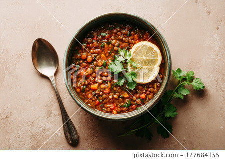 Spicy Vegan Lentil Stew with Cilantro and Lemon on Beige Background 127684155