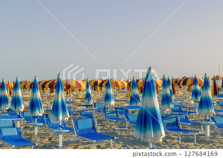 Parasols and sunbeds in Rimini resort beach Parasols and sunbeds in Rimini resort beach 127684169