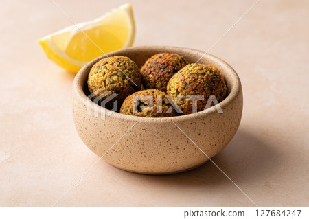 Ceramic Bowl with Baked Lentil Falafels and Lemon on Beige Background 127684247