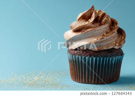Chocolate Cupcake with Swirled Frosting and Gold Dust on Blue Background Chocolate Cupcake with Swirled Frosting and Gold Dust on Blue Background 127684343
