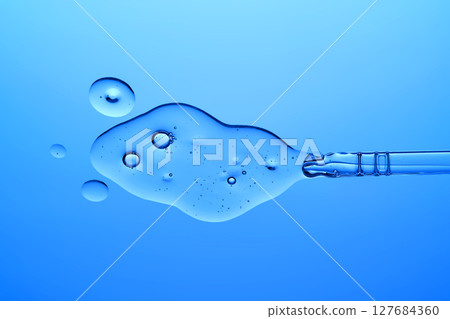 A dropper with a transparent serum texture on a blue background. A dropper with a transparent serum texture on a blue background. 127684360