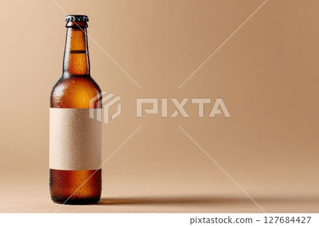Craft Beer Bottle with Blank Label and Condensation on Beige Background 127684427