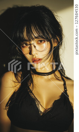 Confident young woman poses with stylish glasses and casual outfit in warm lighting setting 127684530