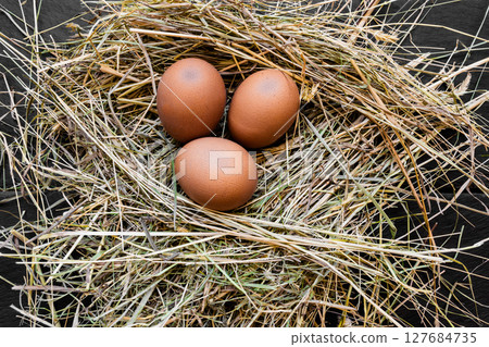 Three Brown Chicken Eggs in Hay Nest 127684735
