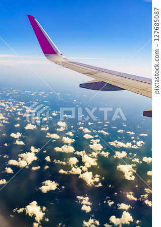View from an airplane window to wing and clouds View from an airplane window to wing and clouds 127685087