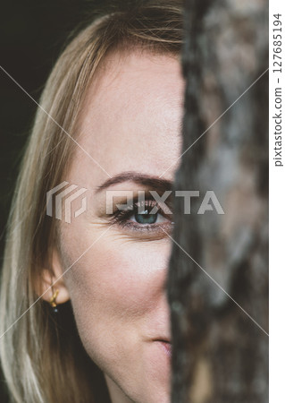 Woman portrait behind the tree 127685194