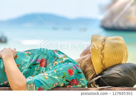 Blonde woman lying on bench and looking to the sea in Thailand Blonde woman lying on bench and looking to the sea in Thailand 127685301