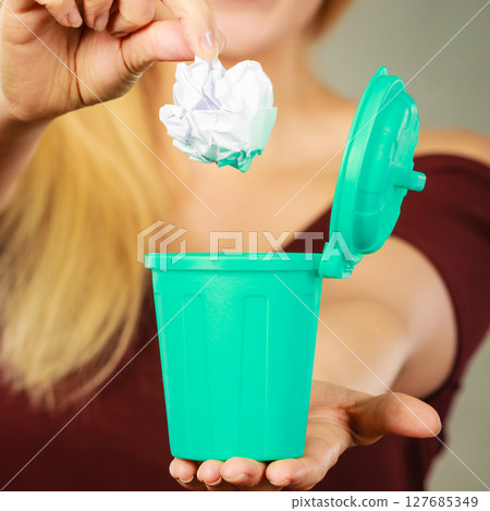 Woman putting paper into small trash can 127685349