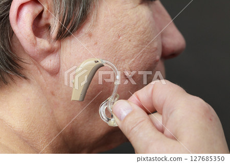 Closeup senior woman using hearing aid Closeup senior woman using hearing aid 127685350