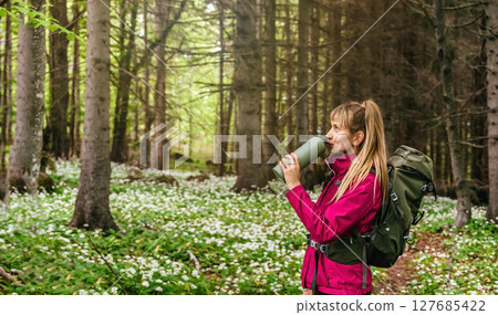 Woman Walking through Blooming Forest Glade 127685422