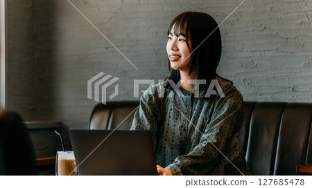 A young woman using a laptop at a cafe 127685478