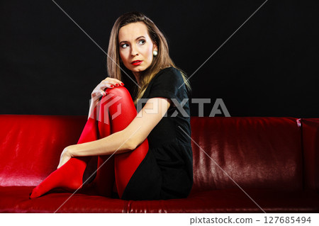 Sad woman sitting on red couch 127685494