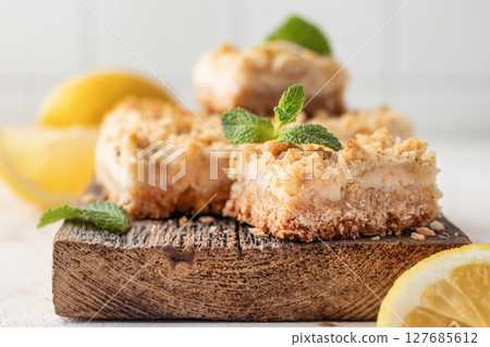 Lemon crumble bars on wooden cutting board close up. Oatmeal lemon bars Lemon crumble bars on wooden cutting board close up. Oatmeal lemon bars 127685612
