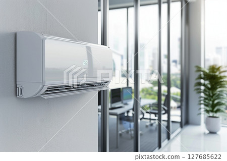 Modern air conditioner mounted on the wall in a bright office space with large windows and greenery, ensuring comfort 127685622