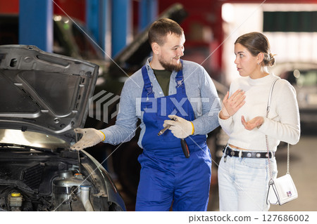 female customer of a car service consults with a mechanic female customer of a car service consults with a mechanic 127686002