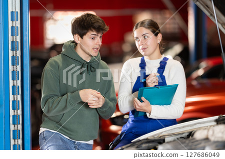 male client consults with a mechanic to repair a car male client consults with a mechanic to repair a car 127686049