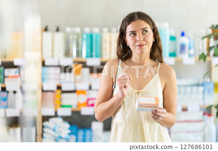 woman chooses a package of pills in the summer at the pharmacy woman chooses a package of pills in the summer at the pharmacy 127686101