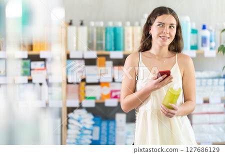 Girl scan barcode on shampoo in pharmacy Girl scan barcode on shampoo in pharmacy 127686129