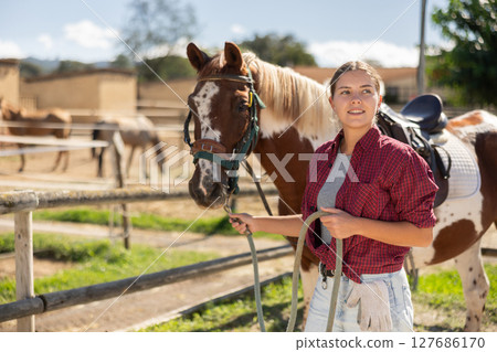 Young woman leads horse by bridle 127686170